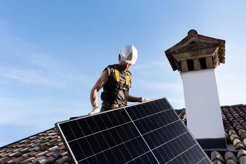 Roofer Installing Solar Panel on Residential Clay Tile Roof. Stock Photos
