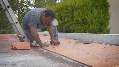 Roofer laying flat terracotta tiles beside ladder Stock-Footage 345695210