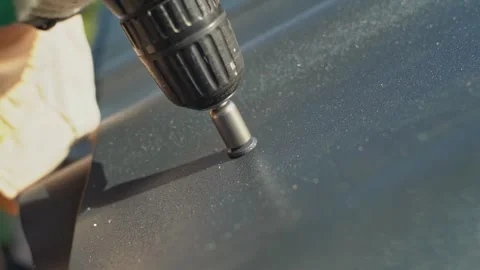 A roofer screws a self-tapping screw into a black metal tile. Screwing a self Video stock 265073053