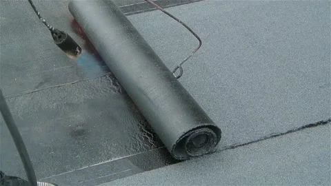 Roofer team lay black roofing material on flat roof Stock Footage 196811477
