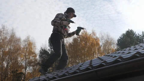 Roofer with two screwdrivers walking on a metal roof without insurance. Stock Footage 163754401