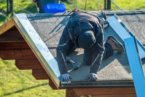 Roofer worker using battery-powered screw gun Stock Photos