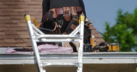 Roofer working on a section in the roof laying out shingles and hammering them Stock Footage 285388361