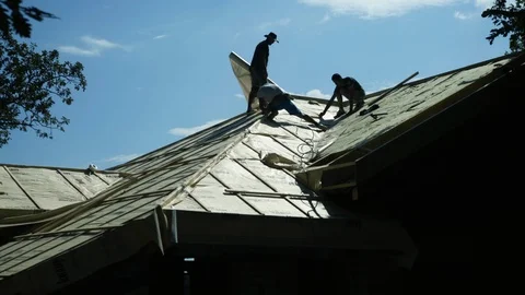 Roofers installing insulation elements on roof construction, workers silhouettes 動画素材 98757368