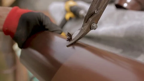 Roofing expert laborer uses a pair of tin snips to cut a hole into a eaves Vídeos de archivo 89739752