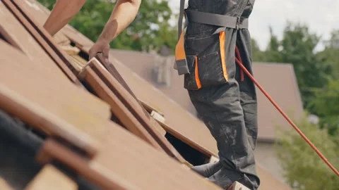 Roofing scene of worker on rooftop removing tiles. Working for solar Stock Footage 201246949