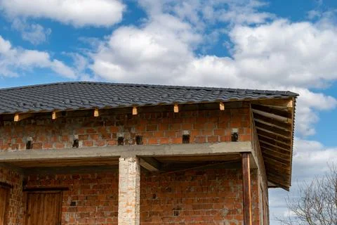 Roofing work involves fitting a metal tile roof on a brick house with a cle.. 스톡 사진