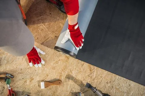 Roofing Worker Installing EPDM Rubber Membrane on Top of Plywood Roof Stock Photos