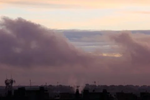 Roofs and chimneys at sunset with clouds and smog Stockfoto's