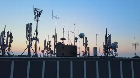Rooftop base station antennas emitting electromagnetic radiation waves. 库存影片 339876620