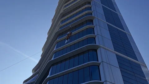 Rooftop BMU crane hoisting massive glass facade panel to skyscraper roof Stock Footage 337359396