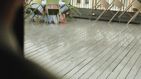 A rooftop cafe is closed due to bad weather. Rain falls on the wooden floor Stock Footage 318064136