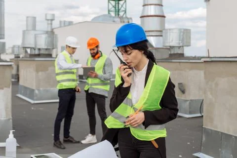 On the rooftop of construction site beautiful engineer make a conversation with Stock Photos