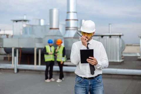 On the rooftop of construction site man engineer make a conversation with some Stock Photos