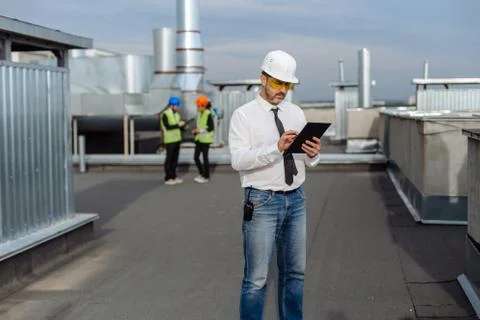 On the rooftop of construction site man engineer make a conversation with some Stock Photos