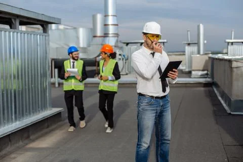 On the rooftop of construction site man engineer make a conversation with some Stock Photos