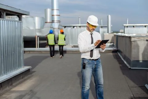 On the rooftop of construction site man engineer make a conversation with some Stock Photos