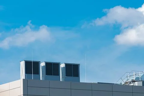 Rooftop cooling units under clear blue sky on sunny day Stock Photos