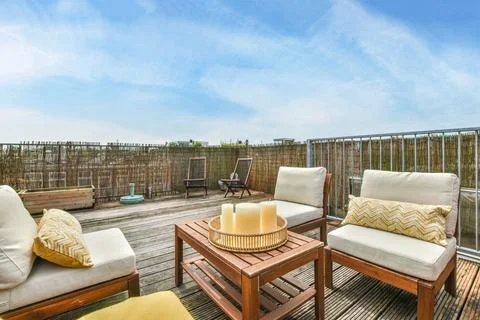 A rooftop deck with chairs and a table with candles Stock Photos