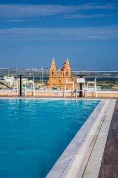 Rooftop infinity pool faces Sanctuary of Our Lady of Mellieha spires Stock Photos