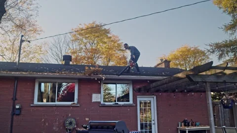 Rooftop leaf blowing by man Stock Footage 321321331