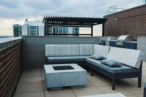 Rooftop lounge area with seating, fire pit, and grill during cloudy weather.. 库存照片