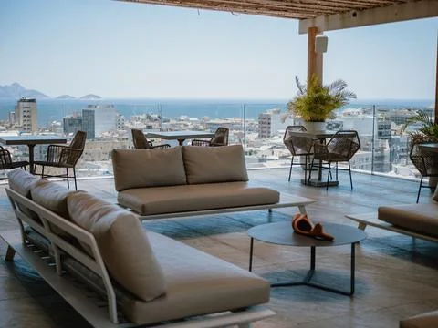Rooftop lounge with sofas overlooking ocean and city Stock Photos