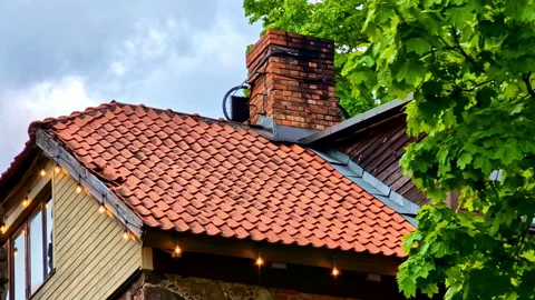 Rooftop with red tiles and old brick chimney among trees Video stock 317296615