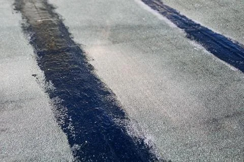 Rooftop surface with dark strips of bitumen sealant applied during repair wor Stock Photos