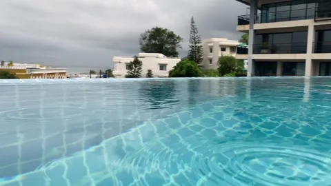 Rooftop swimming pool with clear blue water reflecting the sky and mountains Stock Footage 330767630