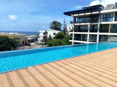Rooftop swimming pool with infinity edge overlooking urban landscape and ocean Stock Photos
