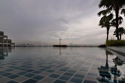 A rooftop swimming pool with a view of a distant city skyline, The water in.. Foto stock