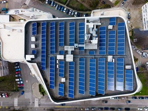 A rooftop in an urban setting features rows of solar panels that capture sunl Stock Photos