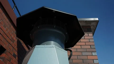 Rooftop ventilation exhaust unit beside brick chimney Stock Footage 346549811