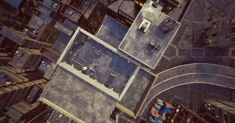 Rooftop view of urban structures with roads and buildings below at midday Ilustración de archivo