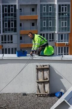 A Rooftop Worker Dressed in High Visibility Gear Engaged in Maintenance Work Stock Photos