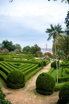 Rooftops and 25 de Abril Bridge above hedges in Belem Lisbon Portugal Stock Photos