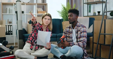 Room design concept where adorable positive young multiracial couple sitting on Stock Footage 158555666