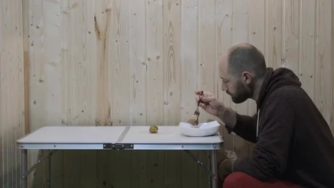 In the room the guy is eating from a plate to him on my knees cat jumps Stock Footage 119822425