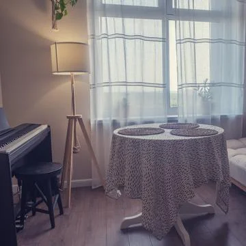Room interior with table, couch and synthesizer. Window with a floor lamp in  Stock Photos
