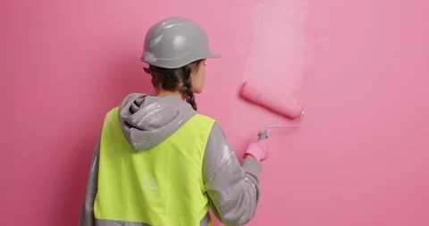 Room interior update. Busy faceless female decorator paints wall in pink dye Stock Footage 155488780