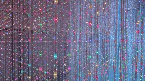 A room with mirror walls full of vertically hanging multicolor LED light stripes Vidéo 333316405