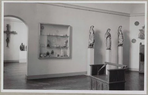Room with small objects in a display case and three images on pedestals; I... Stock Photos