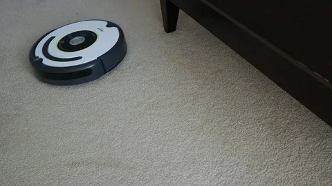 Roomba electronic irobot move around cleans vacuums the white carpet in badroom Stock Footage 73379594