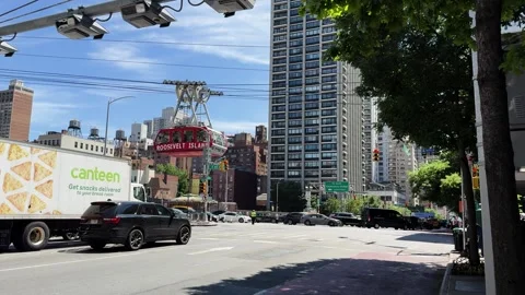 Roosevelt Island Tramway Passing Over Manhattan Street with Traffic and Stock Footage 337406097