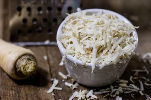 Root of parsley root on grater. Grate and parsley on the old kitchen table in Stock Photos