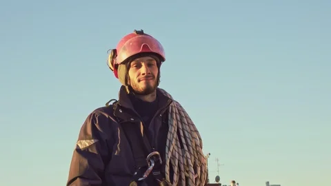 Rope access engineer abseiler with safety harness looks at camera Video stock 125155384