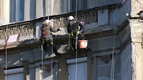 Rope access laborers hanging on wall and working on a beautiful old house facade Stock Footage 169882162