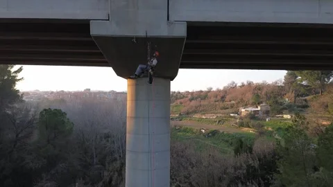 Rope access technician inspecting underside of bridge Stock Footage 306758249