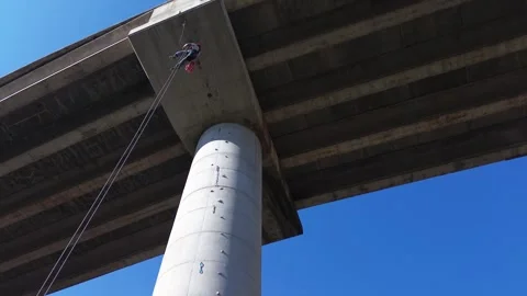 Rope access technician performing inspection and maintenance on bridge Stock Footage 306582134